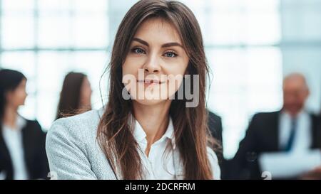 Junge Geschäftsfrau vor dem Hintergrund ihrer Kollegen. Stockfoto