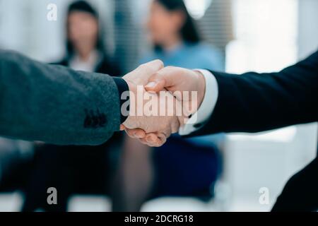 Firm Business Handshake auf einem verschwommenen Bürohintergrund. Stockfoto