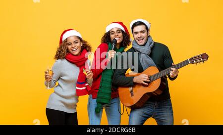 Portrait von verschiedenen Freunden, die Party singen trinken und feiern Weihnachten auf gelbem isoliertem Hintergrund Stockfoto