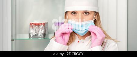 Die Krankenschwester oder Ärztin trägt Schutzhandschuhe, die medizinische Hilfe anziehen Gesichtsmaske im Labor Stockfoto