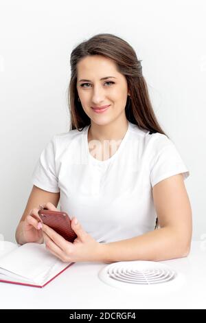 Portrait von jungen lächelnden Kosmetologen mit smatphone im Schönheitssalon Stockfoto