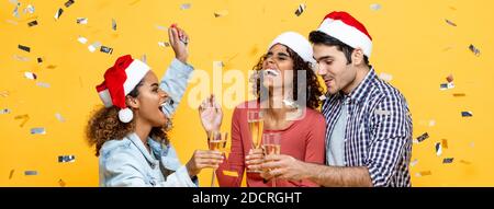 Eine Gruppe von drei glücklichen und vielfältigen Freunden feiert Weihnachten mit Champagner Auf gelbem Studio-Bannrer-Hintergrund Stockfoto