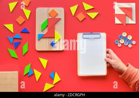 Kreatives Design, Autismus Welttag, Schreibblock in der Hand. Tangram Puzzle, flach lag auf rot, Piktogramm Stockfoto