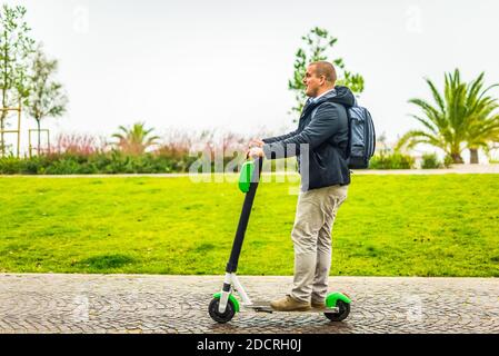 Junge kahle Erwachsene mit einem Elektroroller nach einem Geschäft Treffen auf dem Weg nach Hause.echte Menschen täglich arbeiten Routine.neue Umwelteinbußarbeit Art der Bewegung Stockfoto
