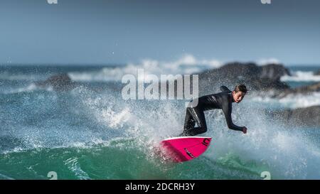 Ein Panoramabild spektakulärer Surfaktion, während ein junger Surfer eine Welle am Fistral in Newquay in Cornwall reitet. Stockfoto