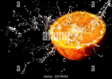Wasserspritzer auf einer saftigen, lebendigen Orange. Dunkler Hintergrund. Stockfoto