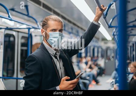 Junger Mann in einer Schutzmaske, der in einem U-Bahn-Auto steht. Stockfoto