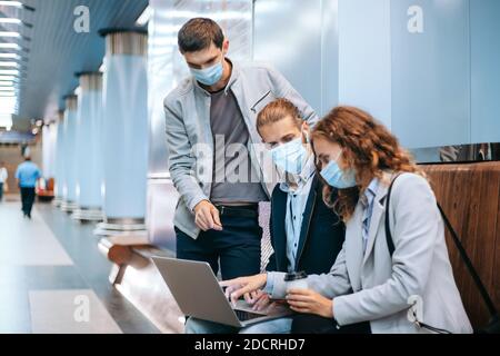 Junge Menschen in Schutzmasken diskutieren Arbeitsfragen auf der U-Bahn-Plattform . Stockfoto