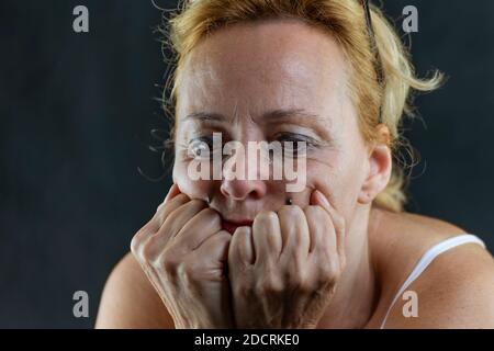 Eine weiße Frau mittleren Alters weint, ihr Gesicht ruht auf Ihre Hände und hat Make-up Tropfen aus ihren Augen Stockfoto