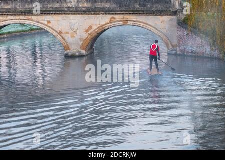 Cambridge, Großbritannien. November 2020. Ein Mann fährt an einem frostigen Morgen mit einem Stand Up Paddle Board durch den Nebel auf der River Cam an der Trinity College Brücke. Die Temperaturen waren fast eiskalt und es gab weit verbreiteten Frost und Nebel zu Beginn eines sonnigen Spätherbsttages. Kredit: Julian Eales/Alamy Live Nachrichten Stockfoto