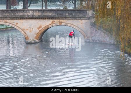 Cambridge, Großbritannien. November 2020. Ein Mann fährt an einem frostigen Morgen mit einem Stand Up Paddle Board durch den Nebel auf der River Cam an der Trinity College Brücke. Die Temperaturen waren fast eiskalt und es gab weit verbreiteten Frost und Nebel zu Beginn eines sonnigen Spätherbsttages. Kredit: Julian Eales/Alamy Live Nachrichten Stockfoto