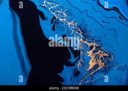Flüssige Kunst. Flüssiges Metallic Gold in abstrakter blauer Welle. Marmoreffekt Hintergrund oder Textur Stockfoto