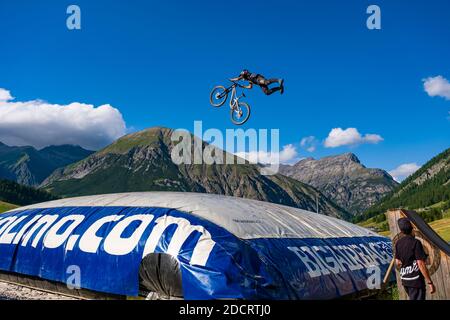 Ein Downhill-Radfahrer übt einen schwierigen Sprung mit der Sicherheit der Landung auf einem großen Airbag im Mottolino Bike Park, die Berge von Livi umgeben Stockfoto