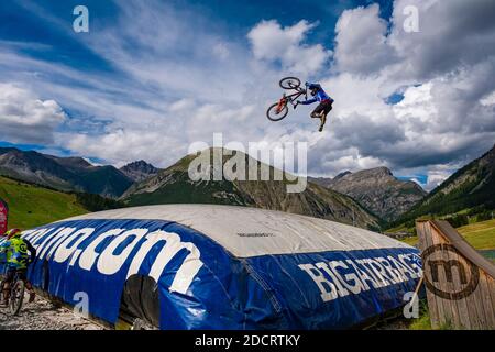 Ein Downhill-Radfahrer übt einen schwierigen Sprung mit der Sicherheit der Landung auf einem großen Airbag im Mottolino Bike Park, die Berge von Livi umgeben Stockfoto