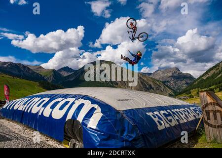 Ein Downhill-Radfahrer übt einen schwierigen Sprung mit der Sicherheit der Landung auf einem großen Airbag im Mottolino Bike Park, die Berge von Livi umgeben Stockfoto