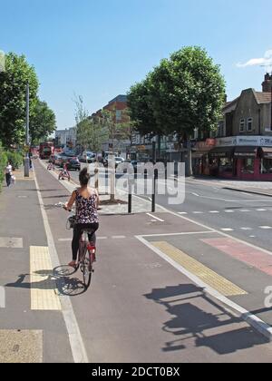 Eine Radfahrerin nutzt den neuen Radweg auf der Lea Bridge Road, London, Großbritannien. Teil des Mini Holland-Programms von Waltham Forest für Radfahren und sicherere Straßen Stockfoto