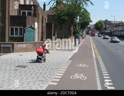 Eine Mutter mit Kinderwagen überquert eine neu renovierte Kreuzung an der Lea Bridge Road, London, Großbritannien. Teil des Mini Holland-Programms von Waltham Forest für sicherere Straßen Stockfoto