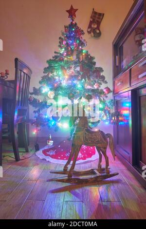 Weihnachtsdekoration im Grunge Zimmer Interieur, Pferd Schaukelstuhl Kinder, klassische Neujahr Baum Stockfoto