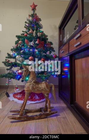 Weihnachtsdekoration im Grunge Zimmer Interieur, Pferd Schaukelstuhl Kinder, klassische Neujahr Baum Stockfoto