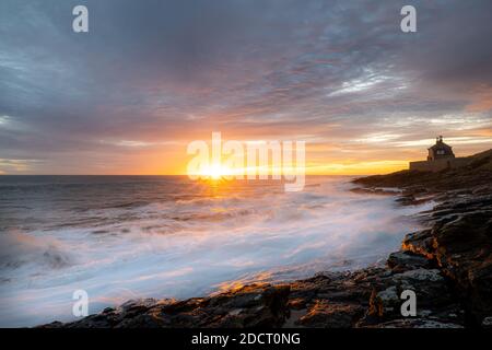 Sonnenaufgang in Northumberland bei Howick. Die Wellen stürzen in die felsige Küstenlinie, während die Sonne über der Nordsee aufgeht. Stockfoto