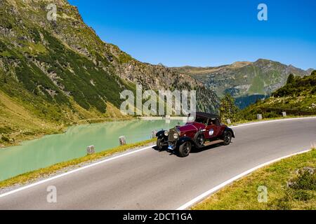 Ein Oldtimer Rolls Royce Phantom I Roadster, der während der Arlberg Classic Car Rally an einem See an der Silvretta Hochalpenstraße vorbeifährt. Stockfoto