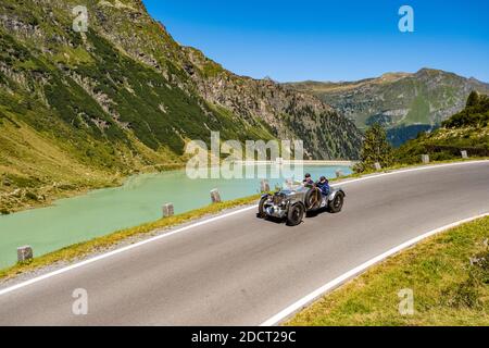 Ein Oldtimer MG TA Midget Special K 3 fährt an einem See entlang der Silvretta Hochalpenstraße während der Arlberg Classic Car Rally vorbei. Stockfoto