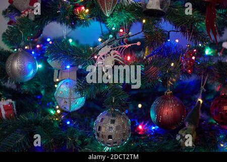 Weihnachtsschmuck auf Weihnachtsbaum mit hängenden Kugeln und Ornamenten und Bokeh Hintergrund. Stockfoto