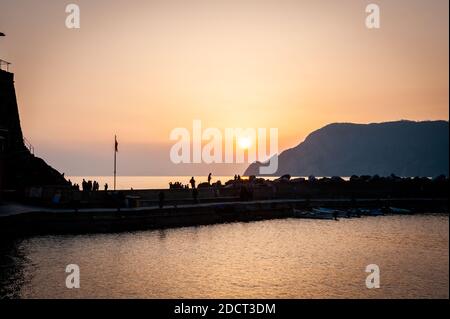 Die Menschen versammeln sich auf dem Pier für den Sonnenuntergang in der Stadt Vernazza, Cinque Terre in der Provinz La Spezia, Italien. Ein UNESCO-Weltkulturerbe. Stockfoto