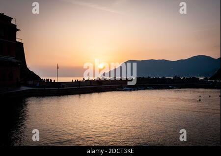 Die Menschen versammeln sich auf dem Pier für den Sonnenuntergang in der Stadt Vernazza, Cinque Terre in der Provinz La Spezia, Italien. Ein UNESCO-Weltkulturerbe. Stockfoto