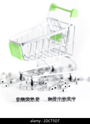 Nahaufnahme am Black Friday geschrieben mit Metallwürfeln mit einem Supermarkt Trolley im Hintergrund Stockfoto