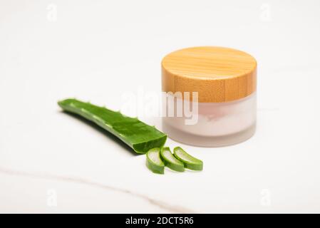 aloe Vera Blatt in der Nähe Scheiben und Behälter von hausgemachten Kosmetik Creme auf weißer Oberfläche Stockfoto