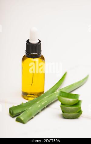 Eine Flasche hausgemachter Aloe Vera Saft in der Nähe von geschnittenen Blättern Weiß Stockfoto