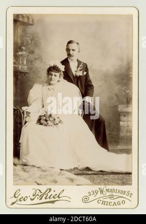 Originalporträt der viktorianischen Hochzeit aus dem späten 19. Jahrhundert aus den 1890er Jahren. Amerikanische Braut und Bräutigam. Viktorianische Bräute und Bräutigame. Amerikaner. Die Frau trägt ein weißes Kleid mit großen Puffärmeln. Viktorianisches Paar aus den 1890er Jahren. Viktorianischer Ehemann und Ehefrau. Foto von Geo,. F. Riel, 339 W. Madison St. Chicago, USA, ca. 1895 Stockfoto