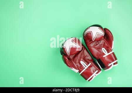 Boxing rote Handschuhe auf grünem Hintergrund, freier Platz. Das Konzept des Umgangs mit Schwierigkeiten. Stockfoto