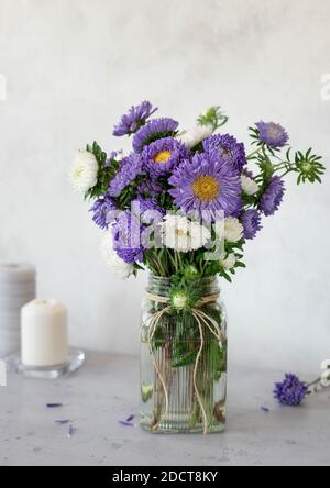 Schönes Bouquet von Flieder und weißen Blumen in einem Glas Vase auf hellem Hintergrund Stockfoto