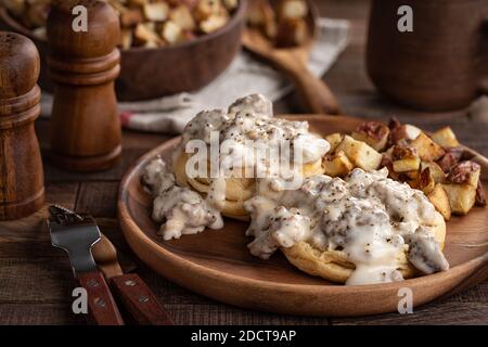 Kekse mit cremiger Wurstsoße und Bratkartoffeln auf einem Holzplatte Stockfoto