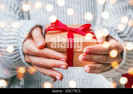 Weibliche Hände halten Geschenkbox mit roter Schleife close-up. Stockfoto