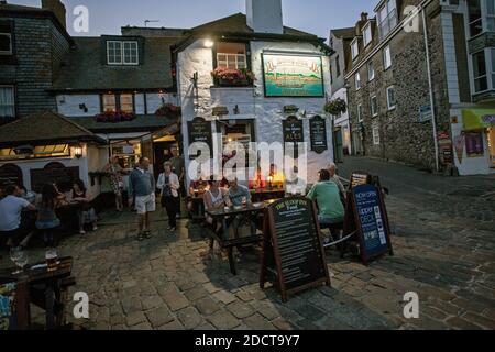 Menschen, die vor dem Pub Sloop Inn in St. Ive's Harbour, Cornwall, Großbritannien, sitzen. Stockfoto