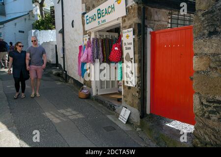 Junges Paar, das in St Ives, Cornwall, Großbritannien, eine enge Straße entlang geht Stockfoto