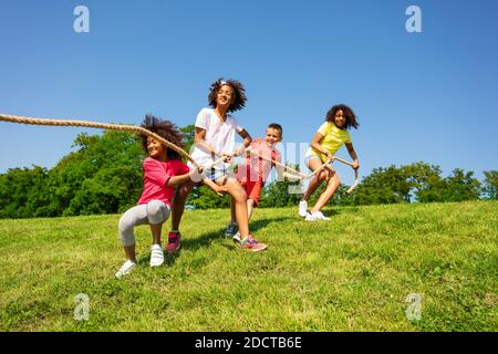 Gruppe von verschiedenen Kindern Junge und Mädchen ziehen Seil Schnur Im Park fallen nach dem Sieg Stockfoto