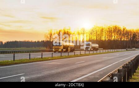 LKW mit Sattelaufliegern in Tanks transportieren Kraftstoff, Schmierstoffe, Benzin und Diesel auf der Autobahn vor dem Hintergrund eines sonnigen Sonnenuntergangs, Kopie sp Stockfoto