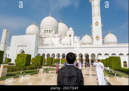 Ein chinesischer Tourist, der die große Moschee aus Marmorstein besucht, auch Scheich-Zayed-Moschee in Abu Dhabi, Vereinigte Arabische Emirate genannt. Stockfoto