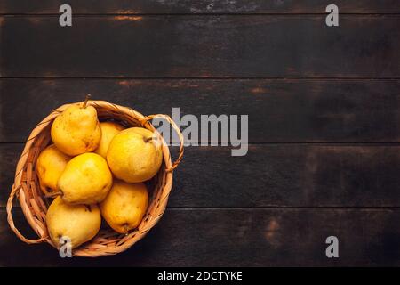 Natürliche Birnenfrucht mit Mängeln im Korb auf dunklem Holzhintergrund. Stockfoto