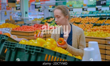 Frau kaufen frische Orange Paprika im Lebensmittelgeschäft Stockfoto