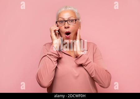 Alte Dame, die mit dem Handy telefoniert und ihrem Freund den neuesten Klatsch erzählt. Stockfoto