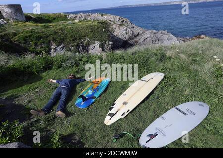 Surfer mit einer Gruppe verschiedener Surfbretter, die auf dem Gras an der zerklüfteten Küste rund um den abgelegenen Little Fistral Beach in Newquay in Cornwall liegen Stockfoto