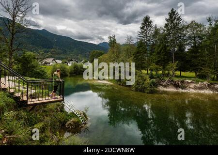 Hölzerner Aussichtspunkt über einem kleinen Fluss mit weißen runden Steinen Am Ufer des Triglav Nationalparks in Slowenien Am bewölkten Herbsttag Stockfoto