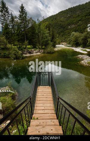 Hölzerner Aussichtspunkt über einem kleinen Fluss mit weißen runden Steinen Am Ufer des Triglav Nationalparks in Slowenien Am bewölkten Herbsttag Stockfoto