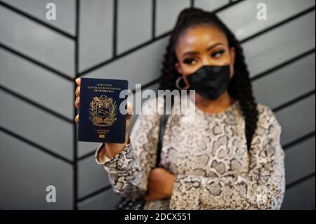 afroamerikanische Frau trägt schwarze Gesichtsmaske zeigen Venezuela Pass in der Hand. Coronavirus in Amerika Land, Grenzschließung und Quarantäne, Virus o Stockfoto