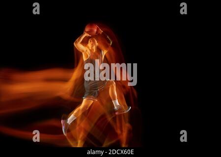 Unaufhaltsam. Junge ostasiatische Basketballspieler in Aktion und Bewegung Springen in gemischtem Licht über dunklen Studio-Hintergrund. Konzept von Sport, Bewegung, Energie und dynamischen, gesunden Lebensstil. Stockfoto